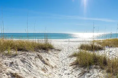 a beach with sand and grass and the ocean at Spring Break Promo! Gulf Front Home with Private Beach Access with Bikes! in Inlet Beach