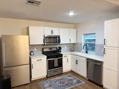 a kitchen with white cabinets and stainless steel appliances at Dreami Stays Panama City - 2BR Retreat Near Downtown, Beaches, & Hot Spots in Panama City