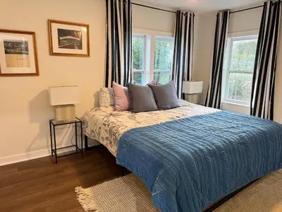 a bedroom with a bed with a blue comforter and two windows at Dreami Stays Panama City - 2BR Retreat Near Downtown, Beaches, & Hot Spots in Panama City