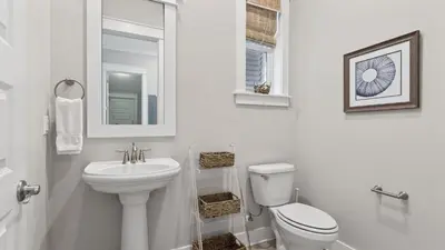 a white bathroom with a toilet and a sink at Arcade Bar Prominence Resort Pool and Gym Access Close to Beach Sea Happy in Watersound Beach