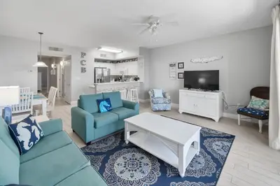 a living room with blue chairs and a tv at Celadon Beach 2107 in Panama City Beach