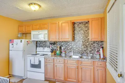 a kitchen with wooden cabinets and a white refrigerator at Sunny Panama City Escape with Pool and Deck! in Panama City