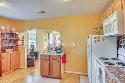 a kitchen with yellow walls and a white refrigerator at Sunny Panama City Escape with Pool and Deck! in Panama City