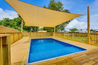 a swimming pool on a wooden deck with a canopy over it at Sunny Panama City Escape with Pool and Deck! in Panama City