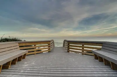 a wooden boardwalk with two benches on the beach at Inns at Seacrest 210 in Seacrest