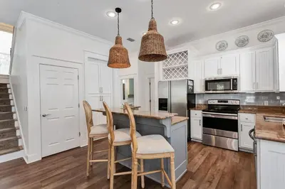 a kitchen with white cabinets and a table and chairs at Seagrove Retreat - Steps to Beach, Pool, and Seaside in Santa Rosa Beach