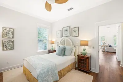 a white bedroom with a bed and a living room at Seagrove Retreat - Steps to Beach, Pool, and Seaside in Santa Rosa Beach