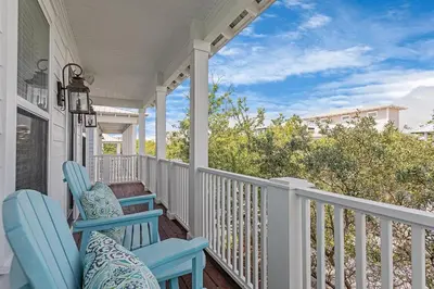 a porch with two blue chairs on a house at Seagrove Retreat - Steps to Beach, Pool, and Seaside in Santa Rosa Beach