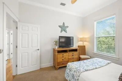 a bedroom with a bed and a tv on a dresser at Seagrove Retreat - Steps to Beach, Pool, and Seaside in Santa Rosa Beach
