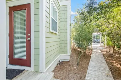 a house with a red door and a sidewalk at Seagrove Retreat - Steps to Beach, Pool, and Seaside in Santa Rosa Beach