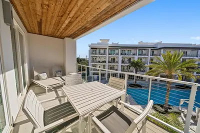 a balcony with tables and chairs and a view of a building at The Pointe at Rosemary Beach 332 in Rosemary Beach