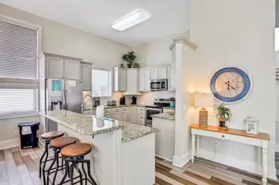 a kitchen with white cabinets and a large clock on the wall at Palazzo 30A in Santa Rosa Beach