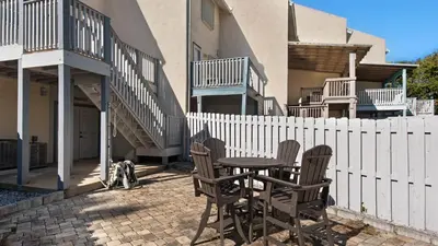 a patio with a table and chairs next to a fence at Palm Sounds in Inlet Beach