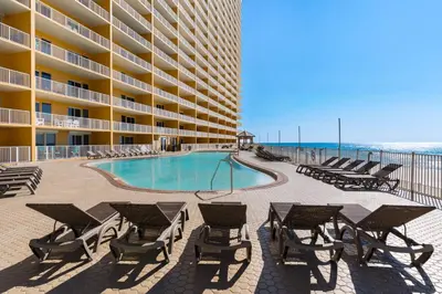 a hotel with a swimming pool and chairs and a building at Treasure Island Unit 905 (2/2) in Panama City Beach
