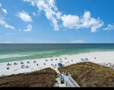 a beach with umbrellas and people on the beach at Sunrise Beach Condo -Gulf front- free beach chair service in Panama City Beach