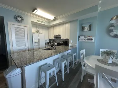 a kitchen with a counter and a table and chairs at Sunrise Beach Condo -Gulf front- free beach chair service in Panama City Beach