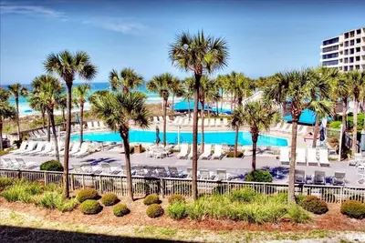 a resort with a pool and palm trees and chairs at Dunes of Panama 1104E in Panama City Beach