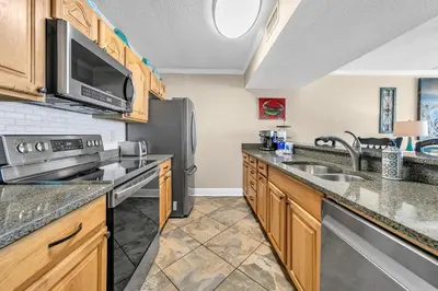 a kitchen with wooden cabinets and stainless steel appliances at Dunes of Panama 1104E in Panama City Beach
