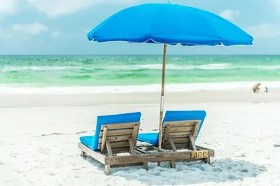 two chairs and an umbrella on a beach at Dunes of Panama 1104E in Panama City Beach