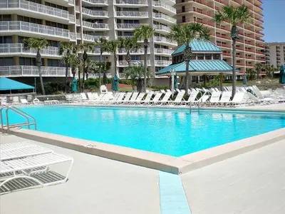 a swimming pool with lounge chairs and a large building at Dunes of Panama 1104E in Panama City Beach