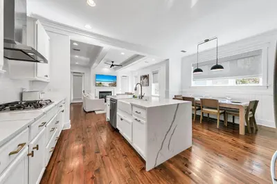 a kitchen and dining room with white cabinets and a table at Available for Season! After Dune Delight at Nature Walk in Santa Rosa Beach