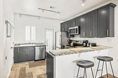 a kitchen with black cabinets and two bar stools at Available for Season! One Life One Love Gulf-Front Townhome in Seagrove Beach