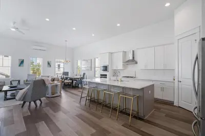 a kitchen and living room with white cabinets and a table at The Richest Peasant at Inlet Beach in Inlet Beach