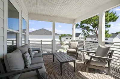 a porch with a couch and a table and chairs at The Richest Peasant at Inlet Beach in Inlet Beach