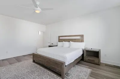 a white bedroom with a large bed and a rug at The Richest Peasant at Inlet Beach in Inlet Beach