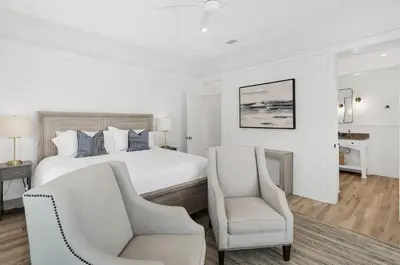 a white bedroom with a bed and two chairs at Available for Season! Seagrove Harbor 30A - Private Pool in Seagrove Beach