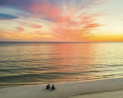 three people sitting on the beach at sunset at Available for Season! Sand Castle at Seagrove Beach in Santa Rosa Beach