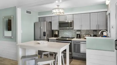 a kitchen with white cabinets and a white table at Sand Cliffs 108 in Seacrest