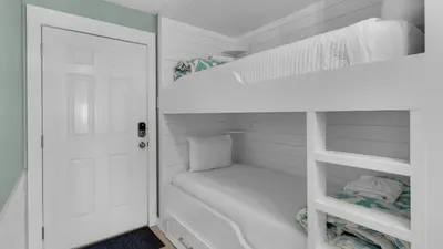 a white bunk room with a white door and bunk beds at Sand Cliffs 108 in Seacrest