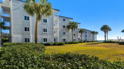 a large apartment building with palm trees in front of the ocean at Sand Cliffs 108 in Seacrest
