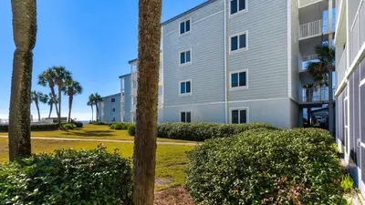 a building with palm trees in front of a building at Sand Cliffs 108 in Seacrest