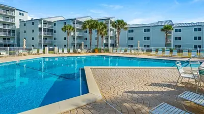 a swimming pool with chairs and a building at Sand Cliffs 108 in Seacrest