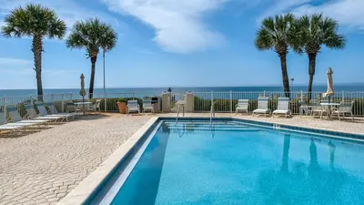 a swimming pool with palm trees and the ocean at Sand Cliffs 108 in Seacrest