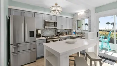 a kitchen with white cabinets and a table with chairs at Sand Cliffs 108 in Seacrest