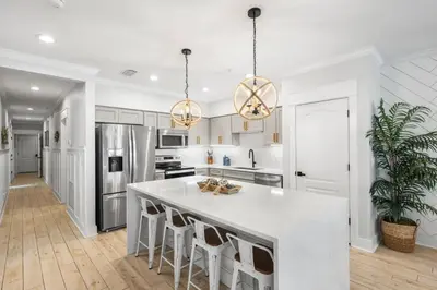 a kitchen with a large white island with bar stools at Available for Season. Gone Coastal at Seacrest in Inlet Beach