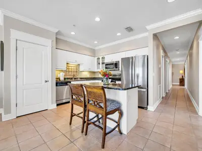 a kitchen with white cabinets and a counter with two chairs at Penthouse Paradise Condo at Seacrest in Rosemary Beach