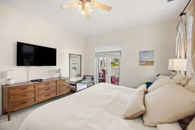 a bedroom with a white bed and a flat screen tv at Seacrest Beach Gem with Shared Pool and Game Room in Seacrest