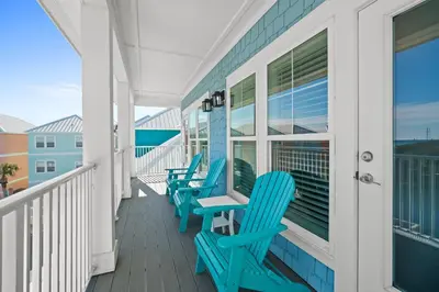 a row of blue chairs on a balcony at Beach House - Riviera Retreat by Panhandle Getaways in Panama City Beach