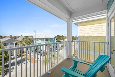 a balcony with a blue chair and a view of a street at Beach House - Riviera Retreat by Panhandle Getaways in Panama City Beach