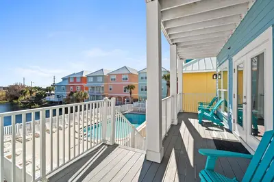 a balcony with chairs and a swimming pool on a house at Beach House - Riviera Retreat by Panhandle Getaways in Panama City Beach