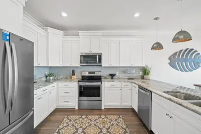 a kitchen with white cabinets and a stainless steel refrigerator at Beach House - Riviera Retreat by Panhandle Getaways in Panama City Beach