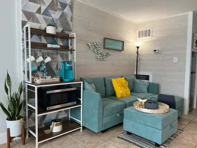 a living room with a blue couch and a tv at Seaview Studio at Top of the Gulf #823 by Nautical Properties in Panama City Beach