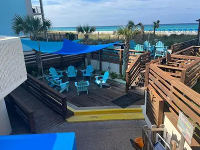a deck with blue chairs and tables and the beach at Seaview Studio at Top of the Gulf #823 by Nautical Properties in Panama City Beach