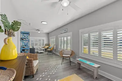 a living room with chairs and a table and windows at Blue Tide Hideaway - Golf Cart, Sznl Hot Tub, Pets OK, FREE Daily Activities, & More! in Panama City