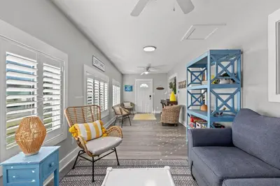 a living room with a blue couch and chairs at Blue Tide Hideaway - Golf Cart, Sznl Hot Tub, Pets OK, FREE Daily Activities, & More! in Panama City