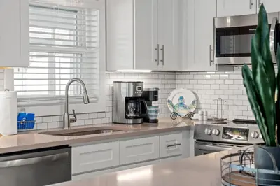 a kitchen with white cabinets and a sink at Blue Tide Hideaway - Golf Cart, Sznl Hot Tub, Pets OK, FREE Daily Activities, & More! in Panama City